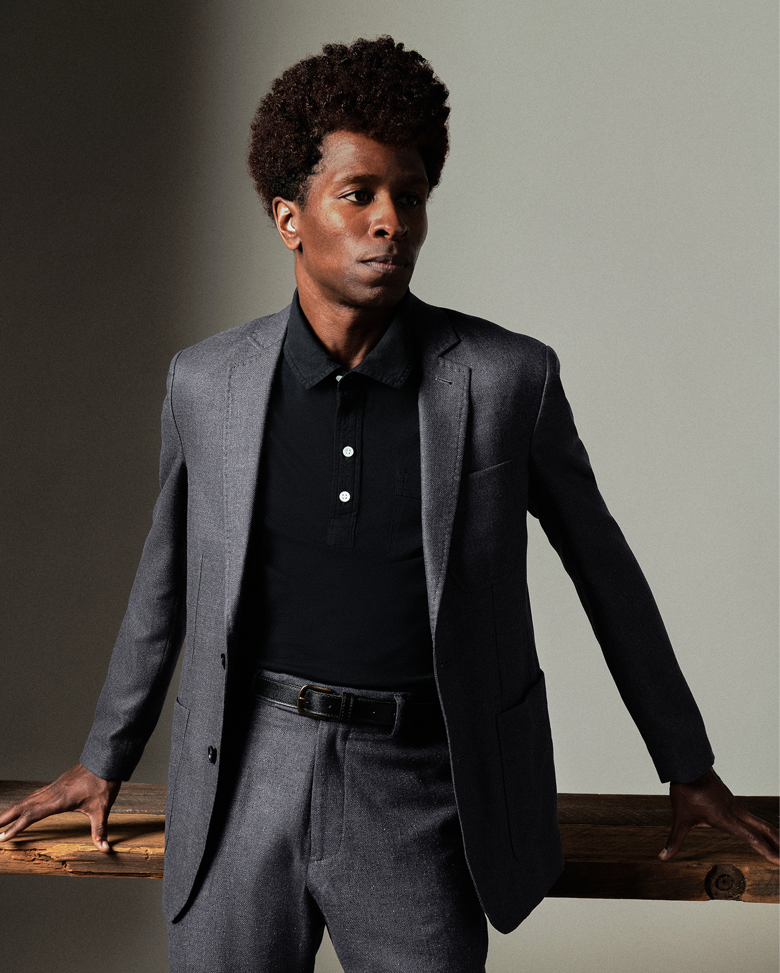 Man wearing a gray suit and black shirt against a neutral background