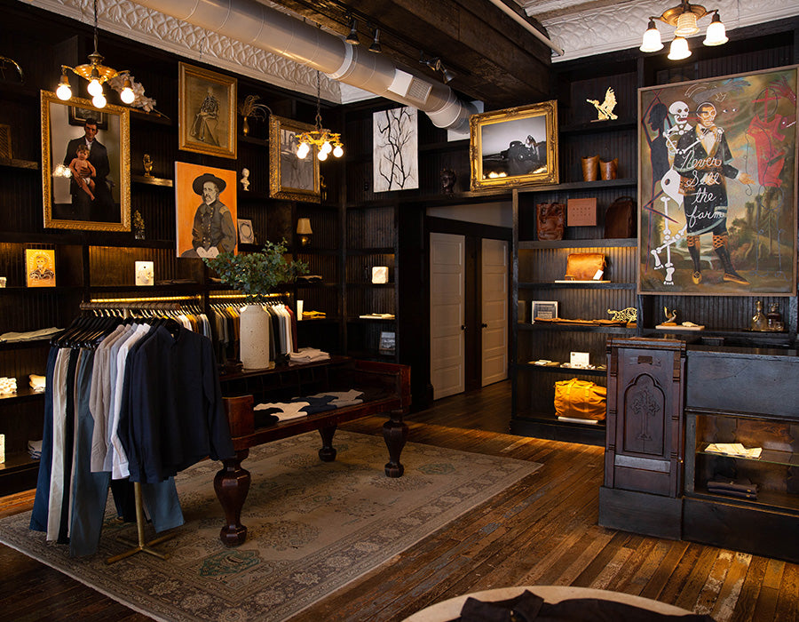 Vintage-style clothing store with wooden interior, hanging clothes, and framed artwork.