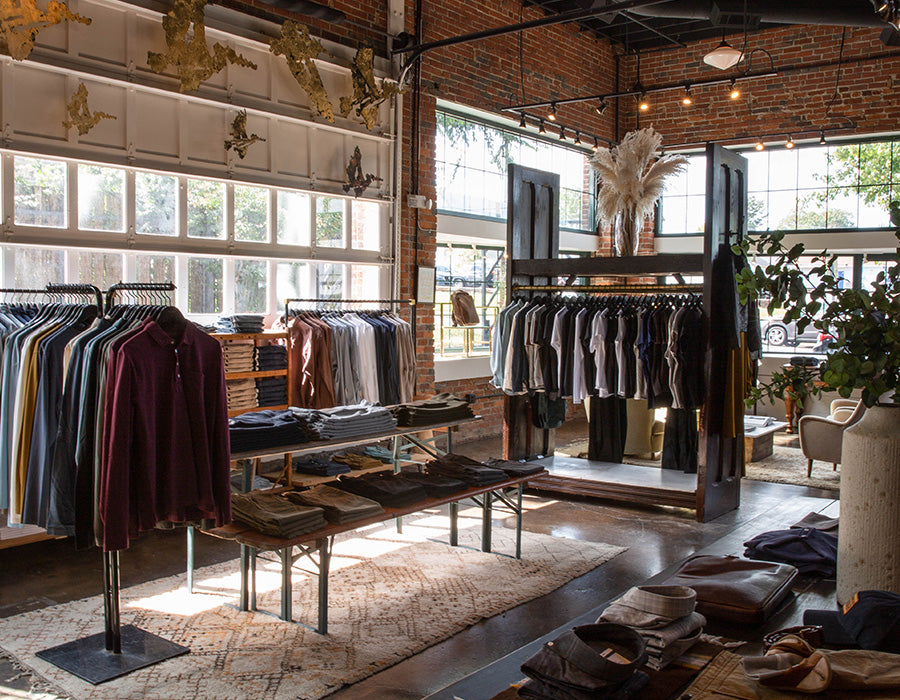 Modern clothing store interior with racks of clothes and large windows.