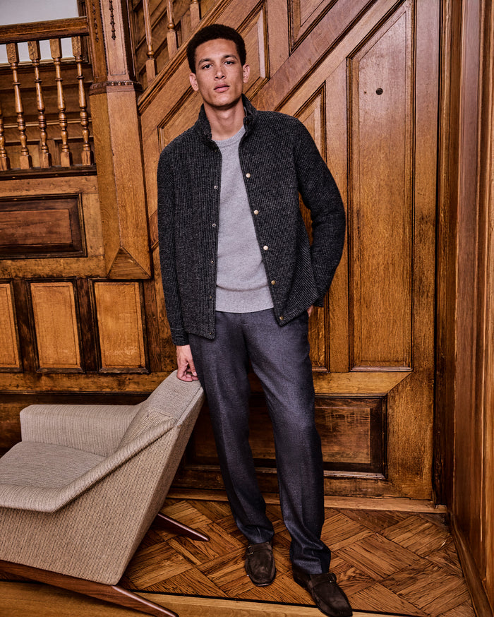Man standing in a room with wooden paneling and a chair.