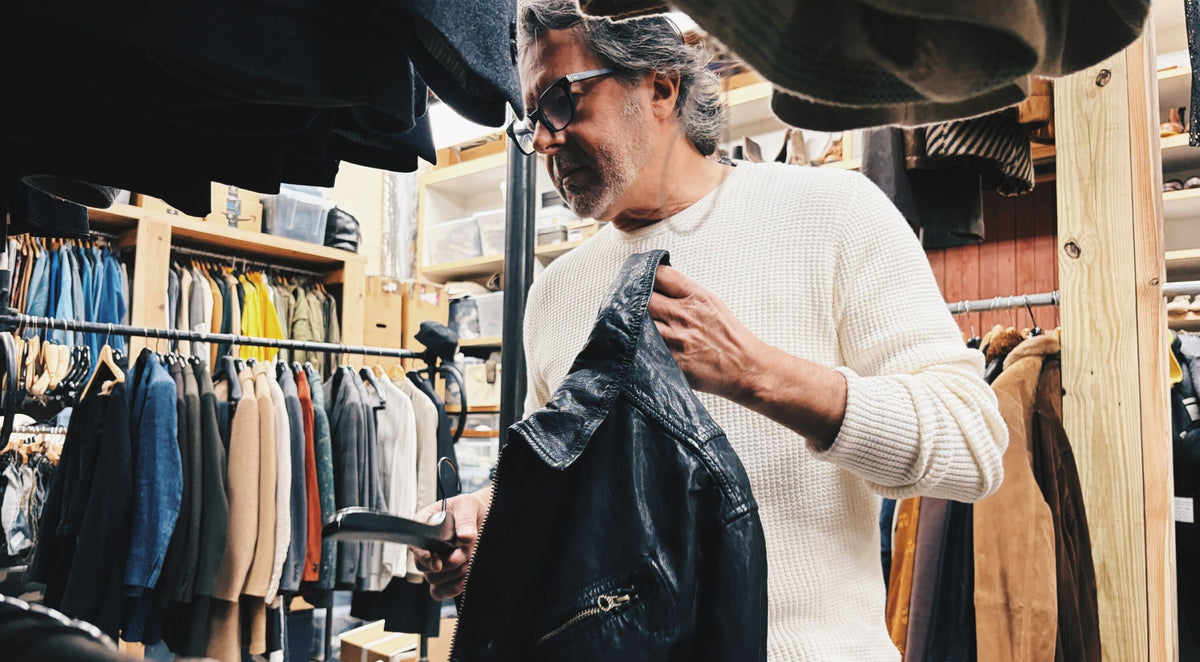 Billy examines a jacket in a clothing store.