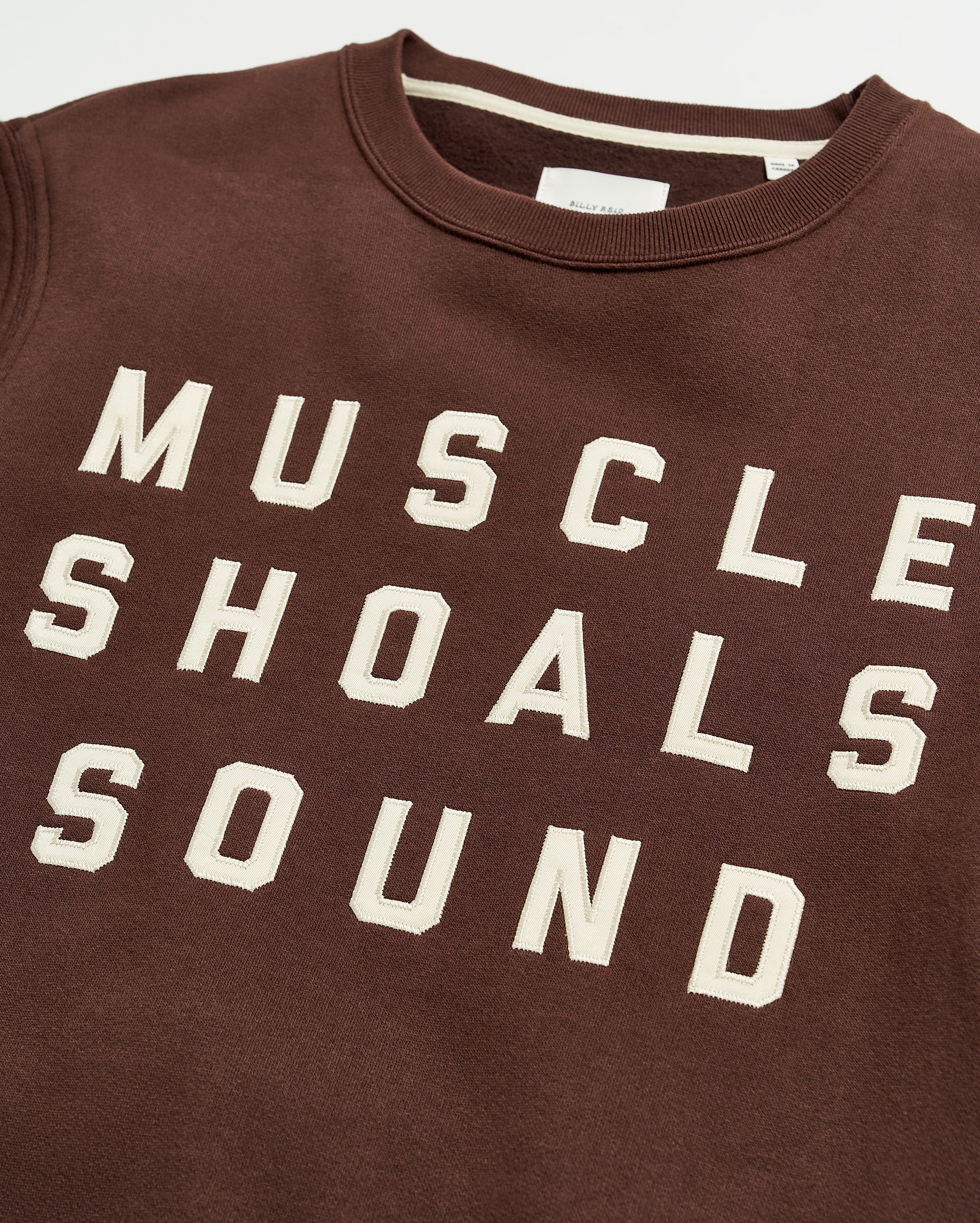 A brown sweatshirt with bold, white block lettering that reads MUSCLE SHOALS SOUND across the front.