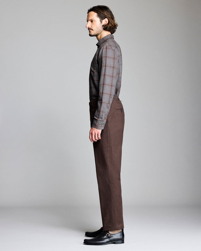 Man wearing a plaid shirt and brown pants on a plain background