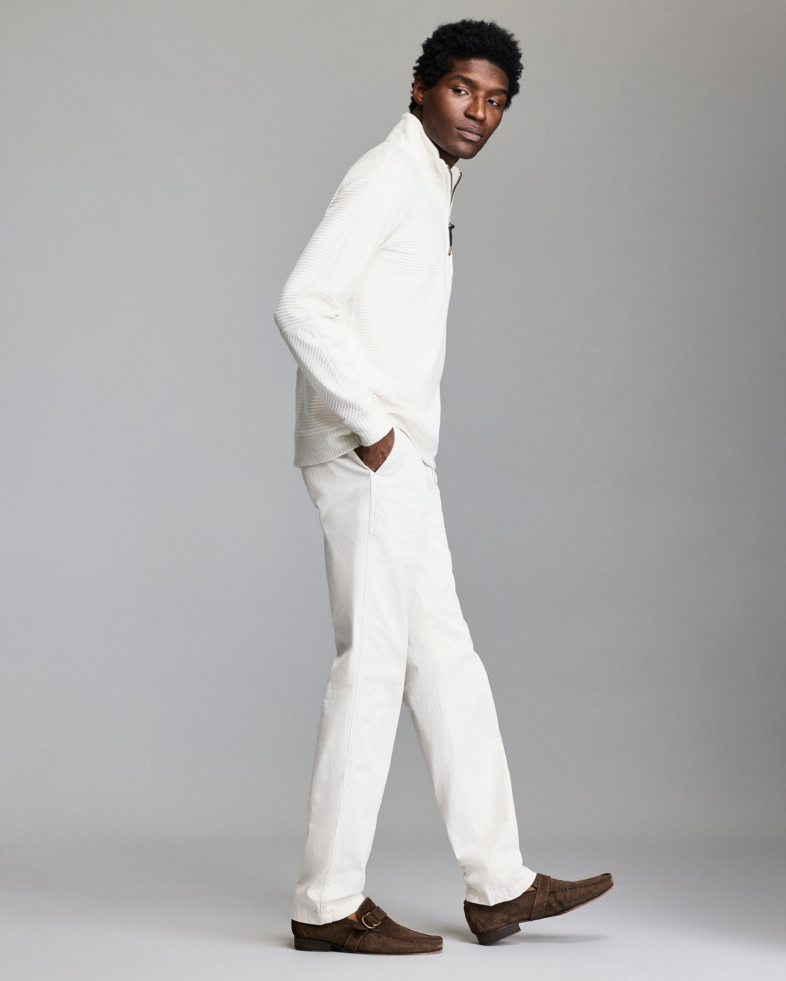 Man wearing a white outfit with brown shoes on a gray background