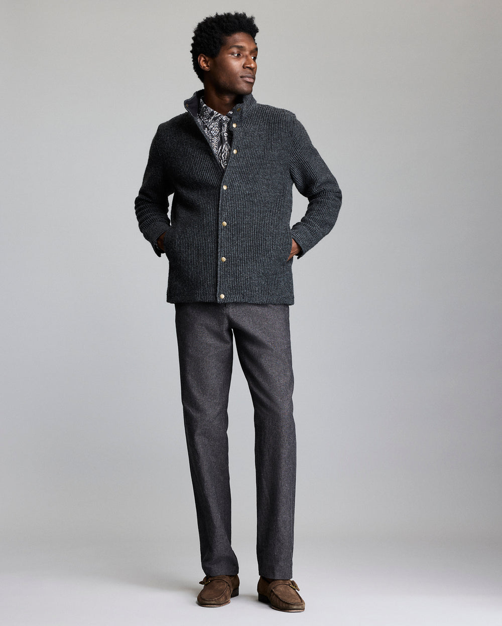 Man wearing a gray textured jacket and pants on a plain background