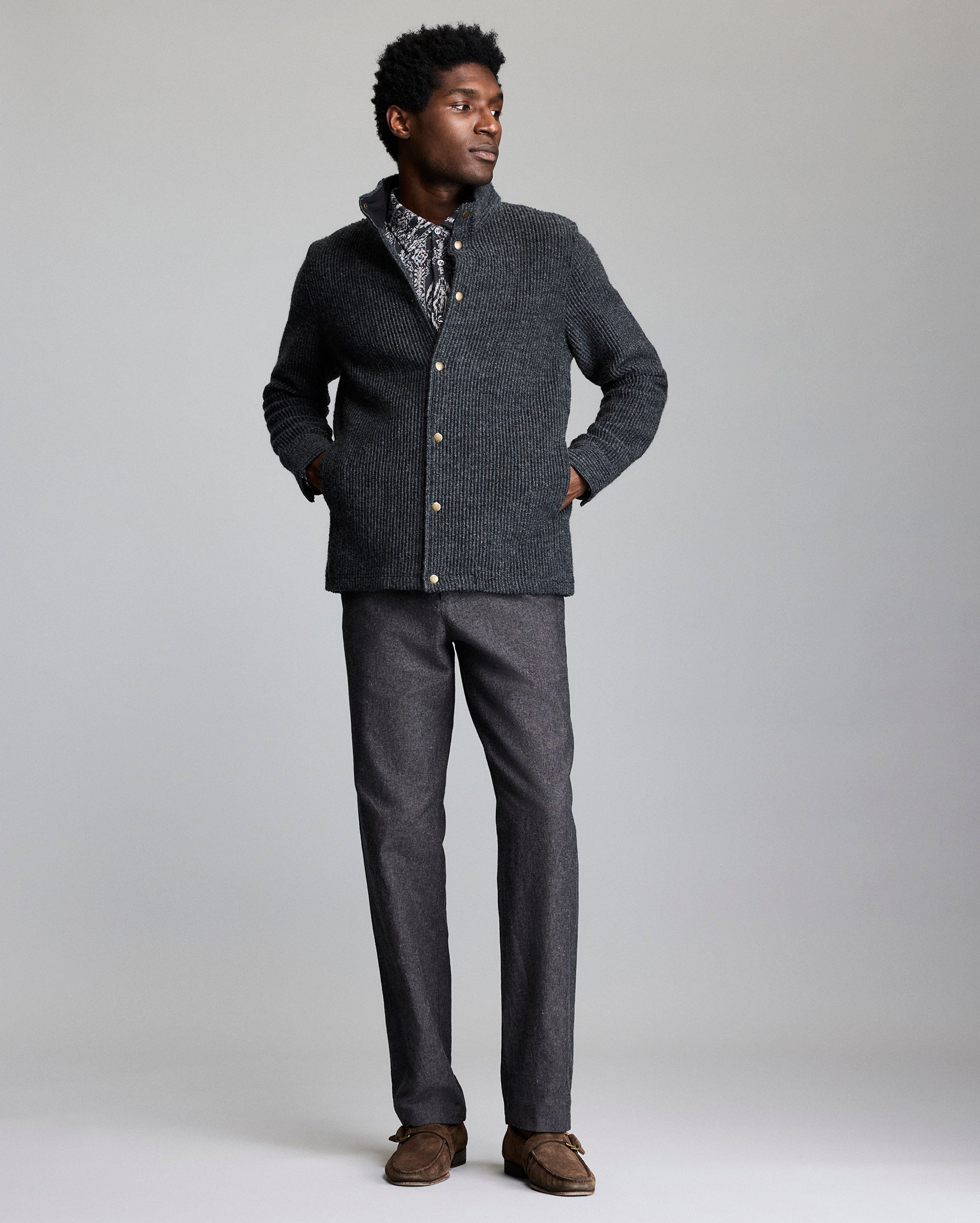 Man wearing a gray textured jacket and pants on a plain background