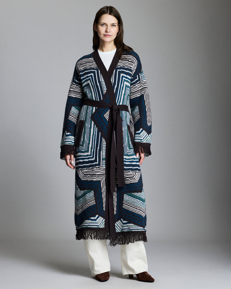 Woman wearing a long, patterned coat against a plain background Alternate