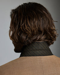 Man with wavy brown hair against a gray background
