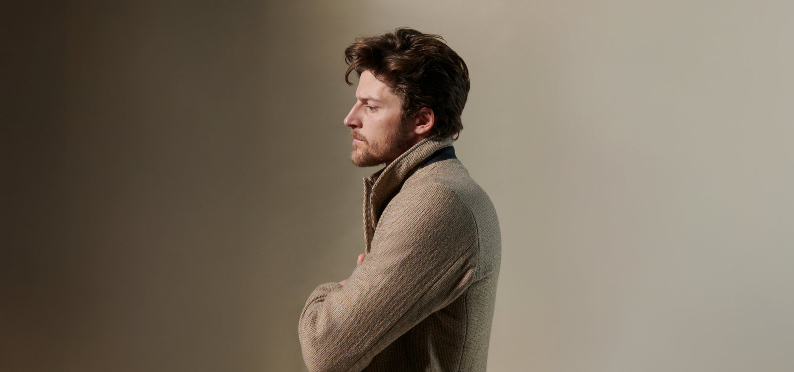 Model wears a tan suit on a beige background.