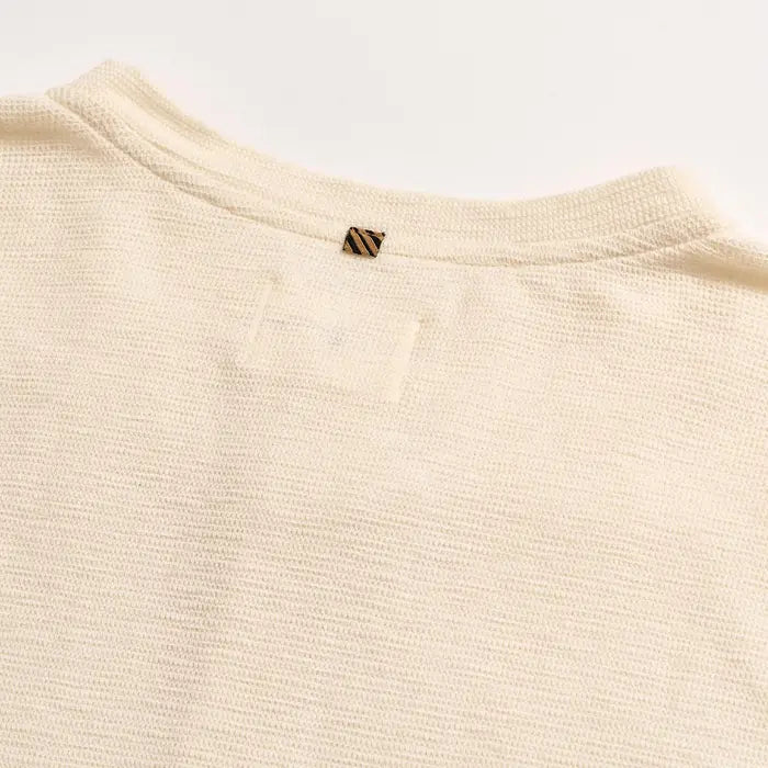 Close-up of a beige textured fabric with a small logo on a white background