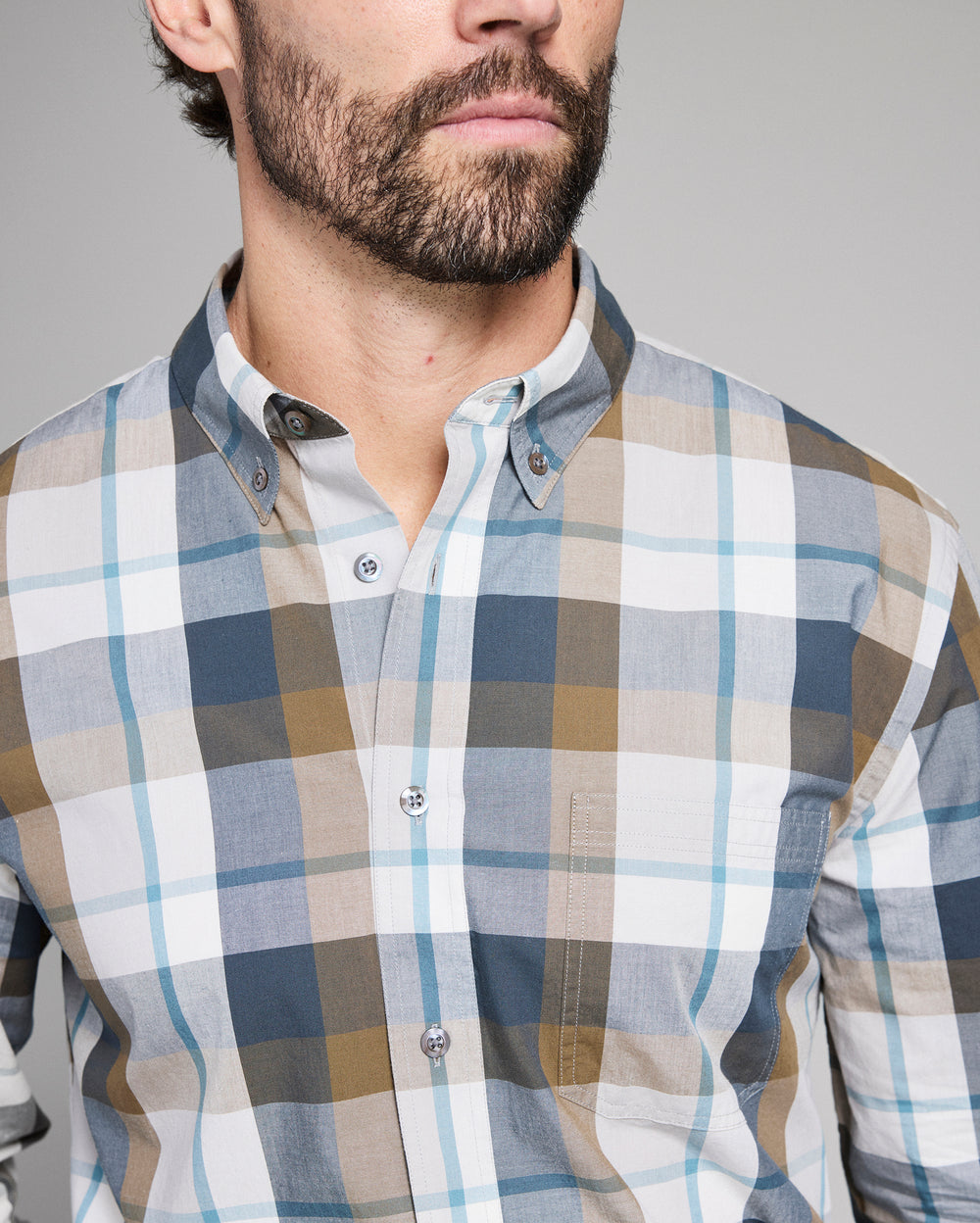 Man wearing a plaid shirt with a neutral background
