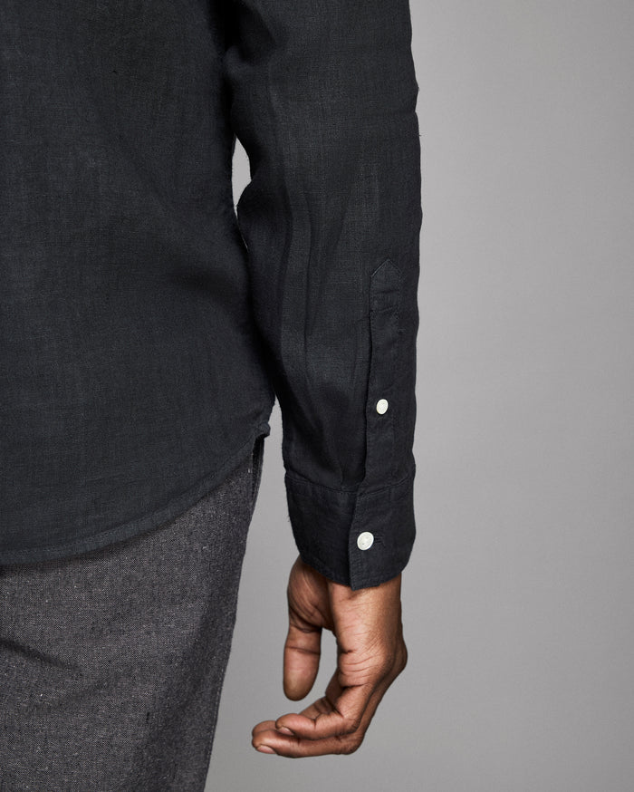Close-up of a person wearing a black shirt with button details on a gray background