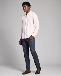 Man wearing a light pink shirt and dark blue pants on a gray background