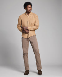 Man wearing a beige shirt and pants with gloves against a gray background
