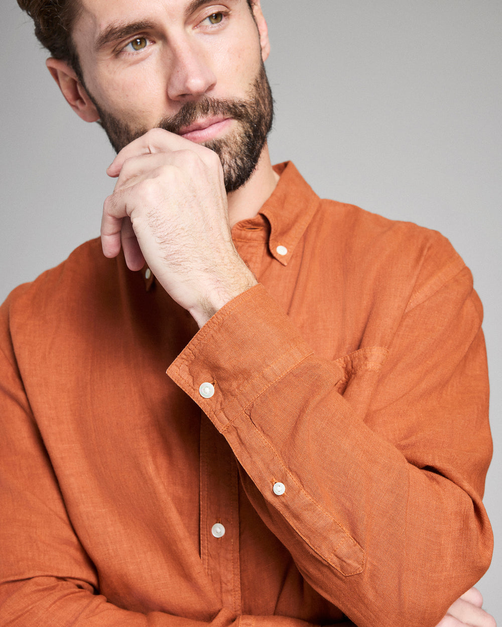 Man wearing an orange shirt with a neutral background
