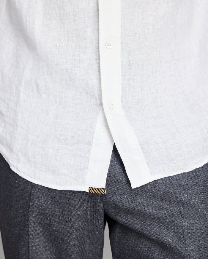 Close-up of a white shirt with a collar and gray pants on a light gray background