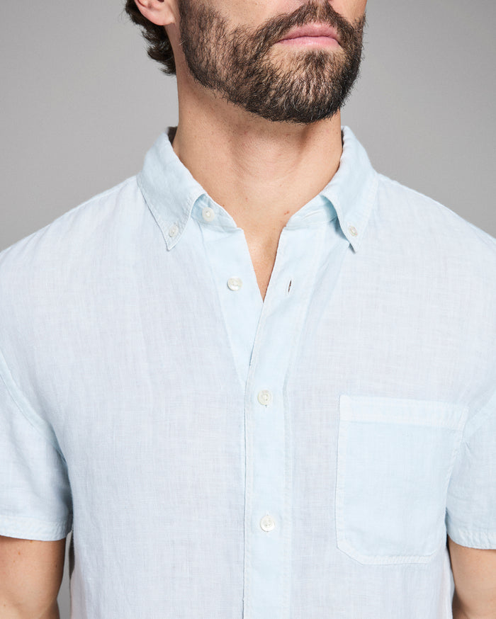 Man wearing a light blue short-sleeve shirt against a gray background