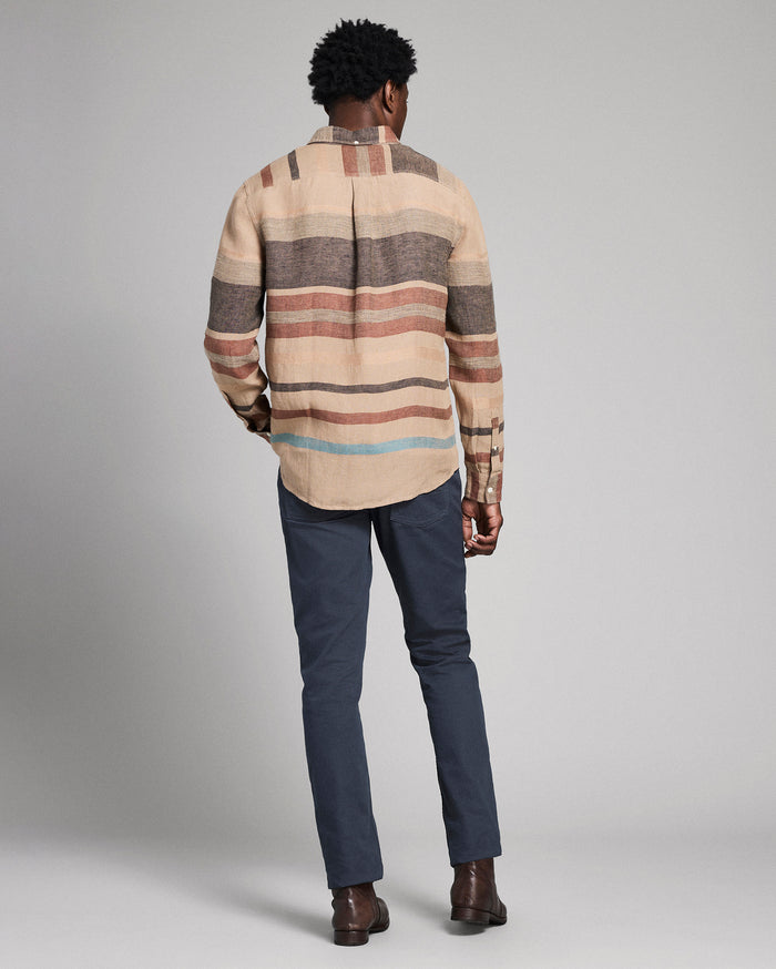Man wearing a striped shirt and dark pants against a plain background