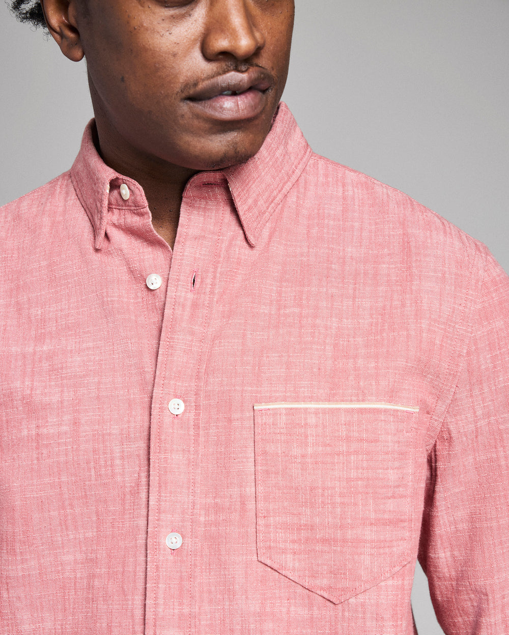 Man wearing a pink checkered shirt against a gray background