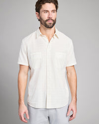Man wearing a white short-sleeve shirt against a gray background
