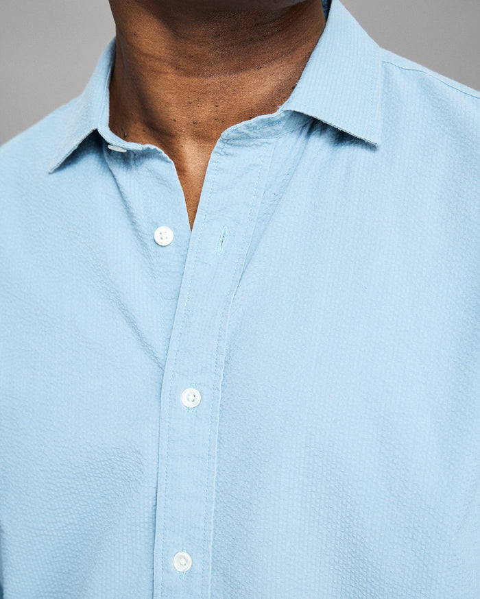 Light blue button-up shirt worn by a person, with a neutral background