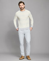 Man wearing a light gray sweater and pants against a gray background