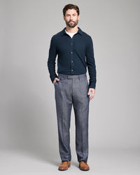 Man wearing a navy sweater and gray pants on a gray background