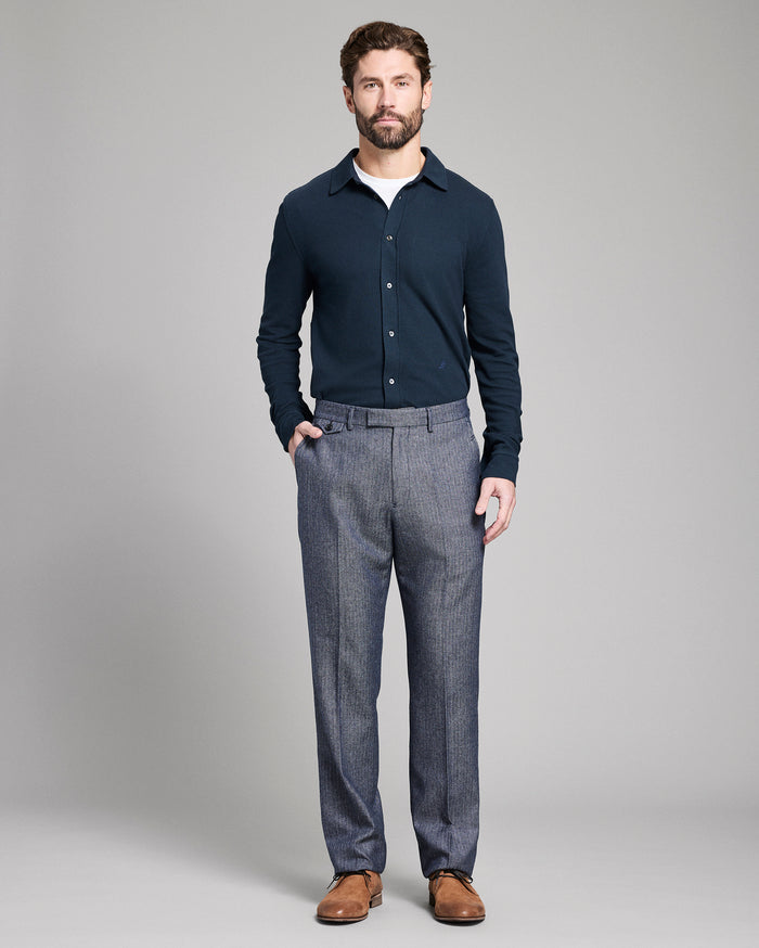 Man wearing a navy sweater and gray pants on a gray background