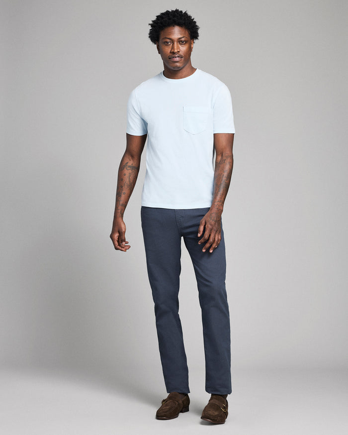 Man wearing a white t-shirt and dark pants on a plain background