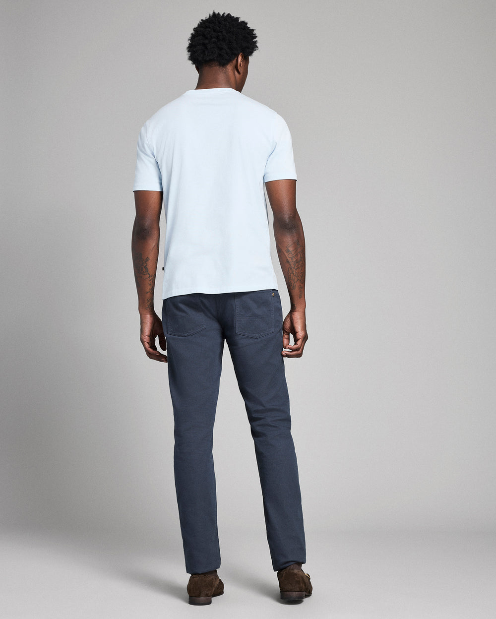 Person wearing a white t-shirt and dark pants on a plain background