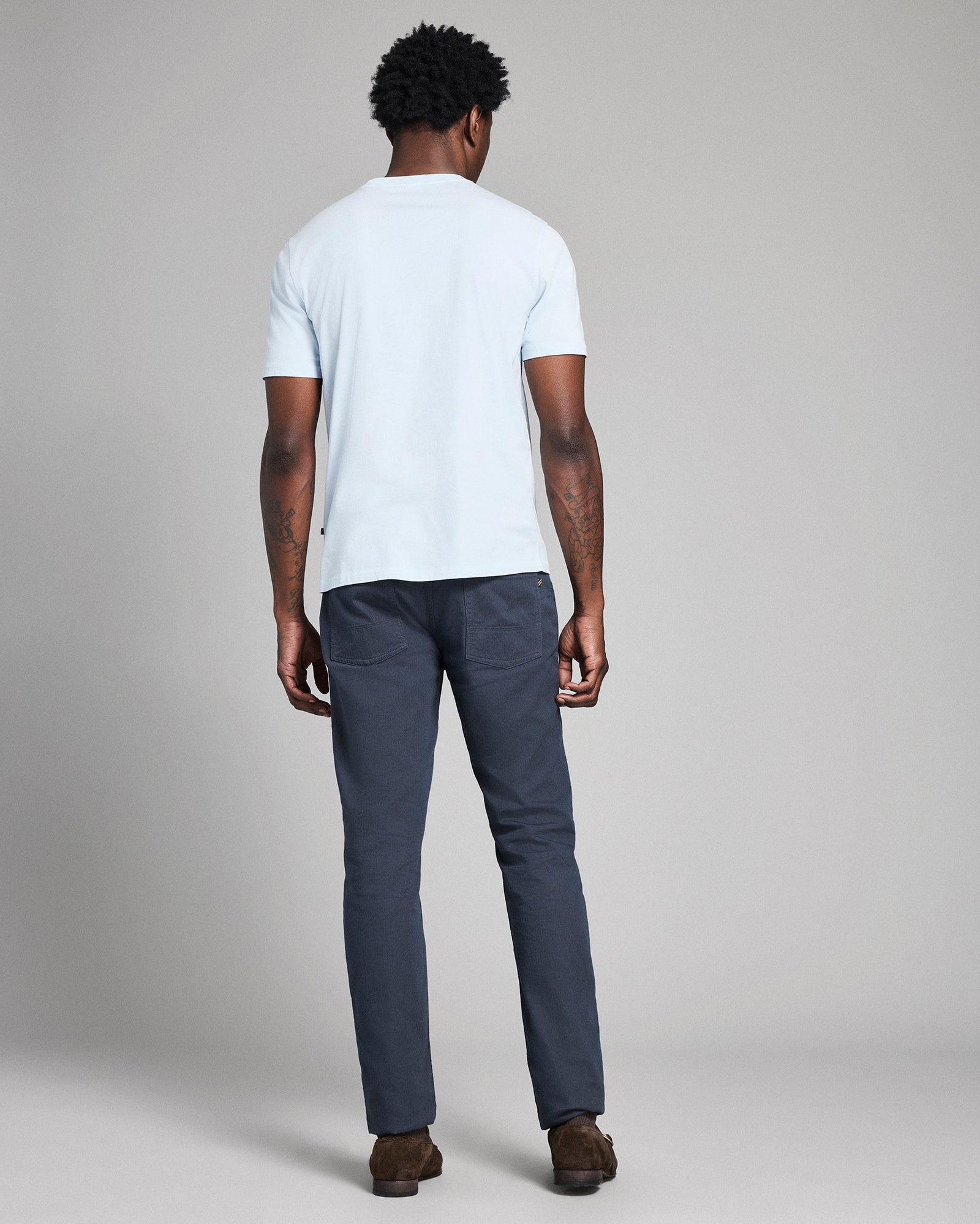 Person wearing a white t-shirt and dark pants on a plain background