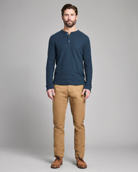 Man wearing a blue long-sleeve shirt and tan pants on a gray background