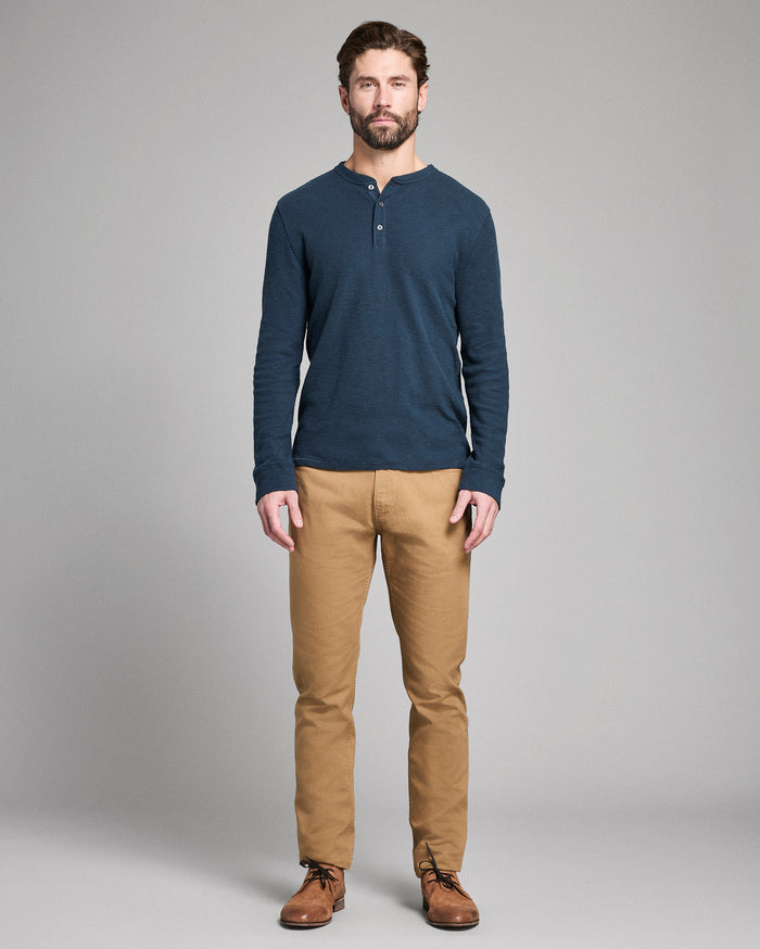 Man wearing a blue long-sleeve shirt and tan pants on a gray background