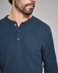 Man wearing a blue henley shirt against a gray background