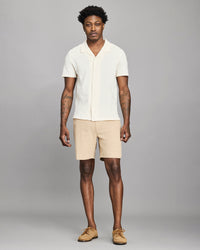 Man wearing a white shirt and beige shorts against a gray background