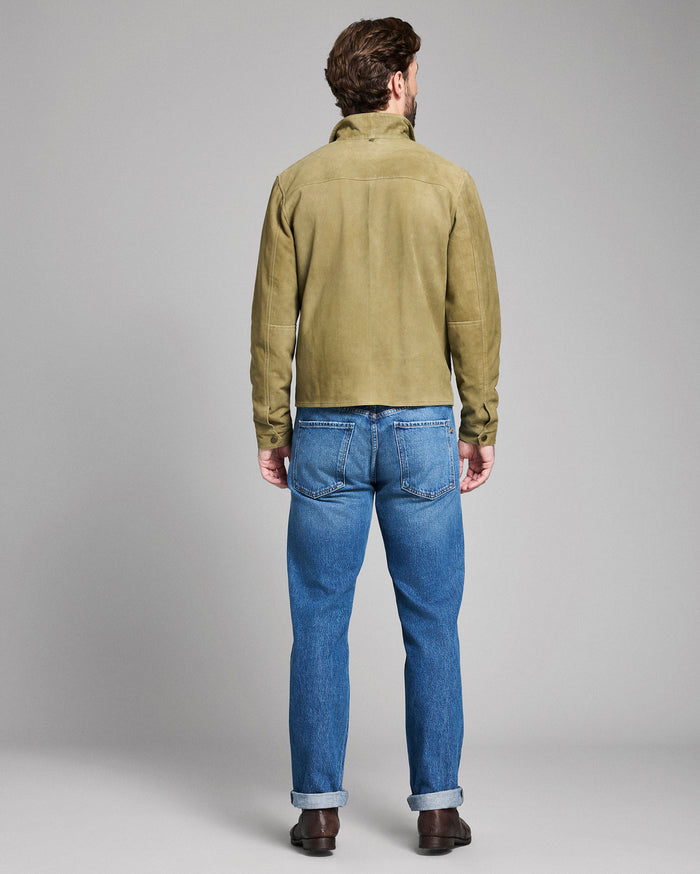 Man wearing a green jacket and blue jeans on a gray background