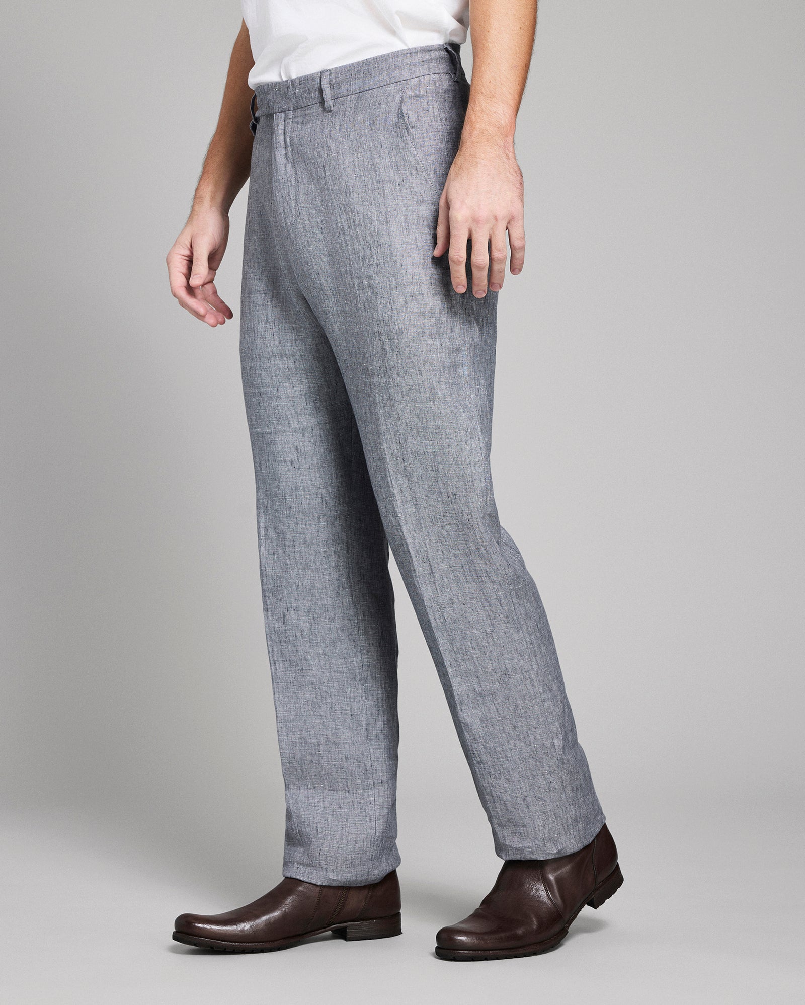 Person wearing gray pants and brown shoes on a plain background