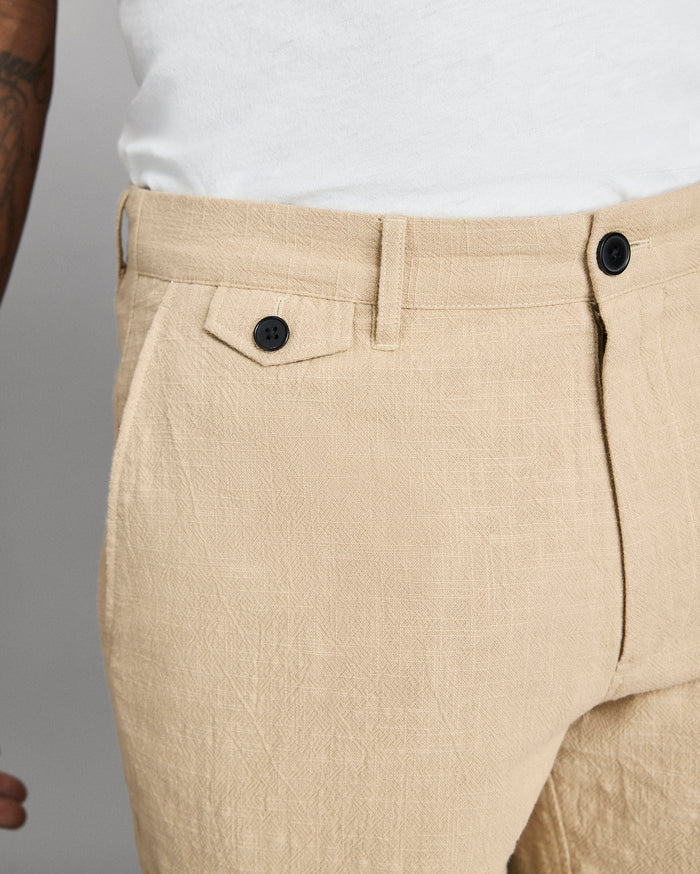 Beige pants with black buttons on a neutral background
