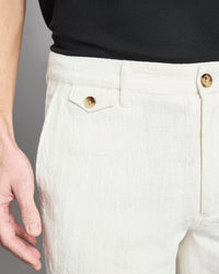Close-up of white pants with gold buttons on a gray background