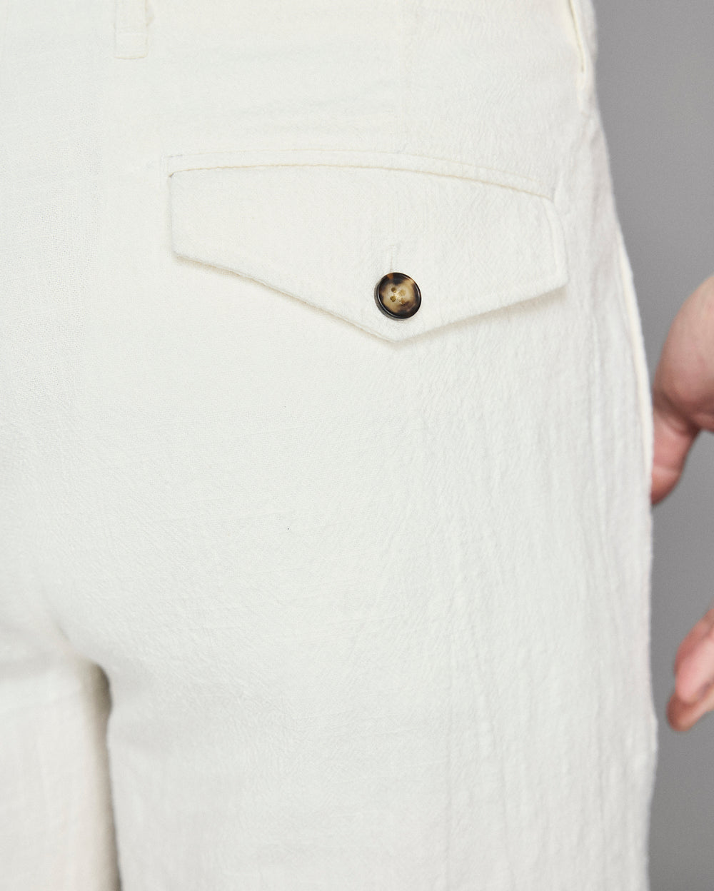 Close-up of a white textured garment with a button on a gray background