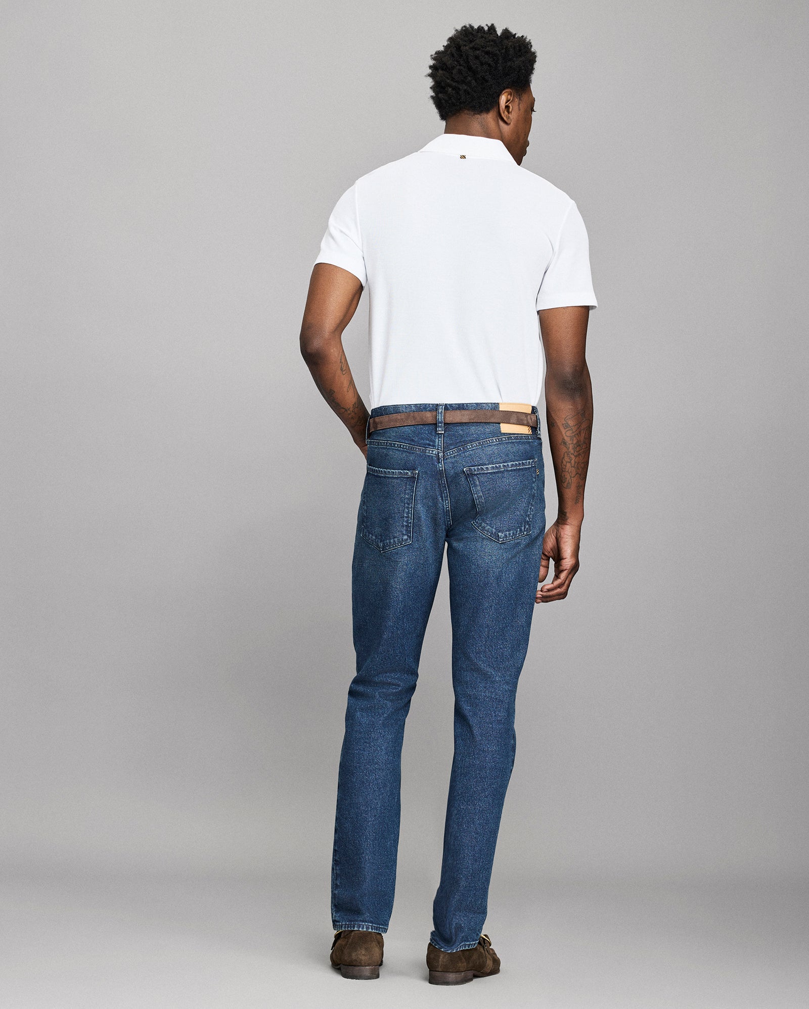 Man wearing blue jeans and a white shirt on a gray background