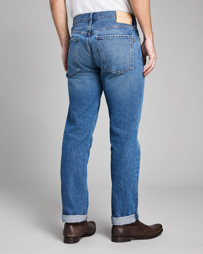 Person wearing blue jeans with a plain background