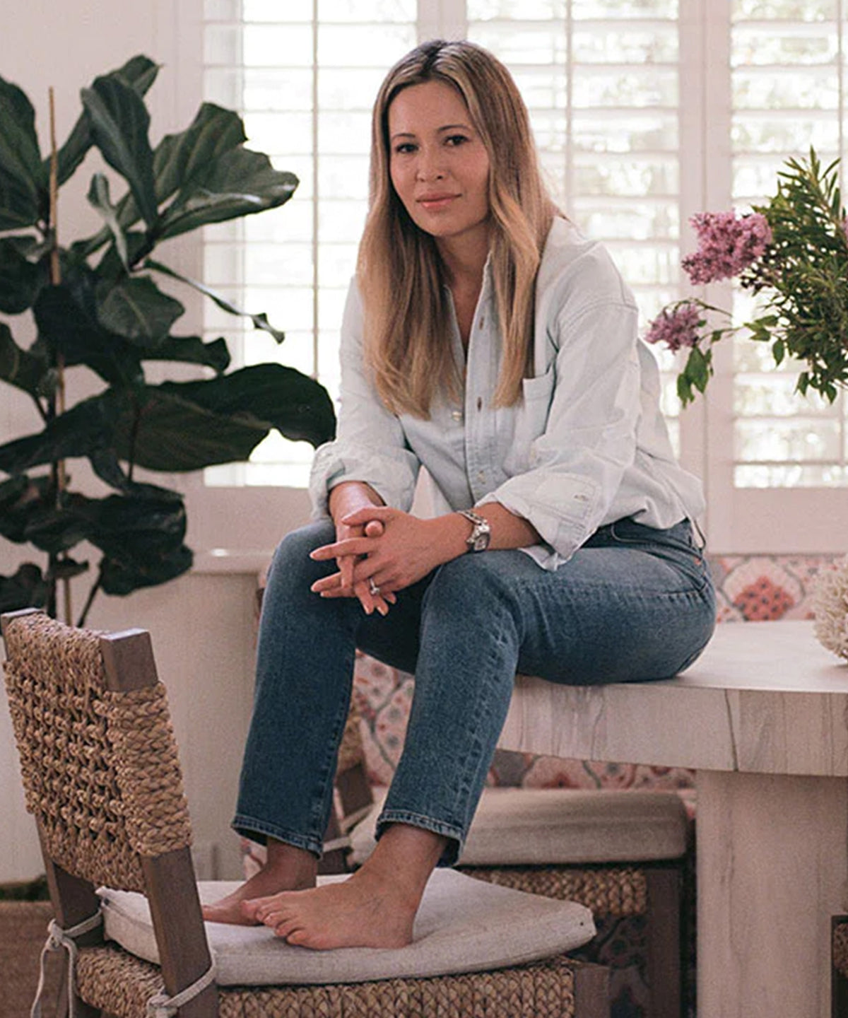 Marianne McDonald, Creative Director at Citizens of Humanity, sits on a table in a white room.