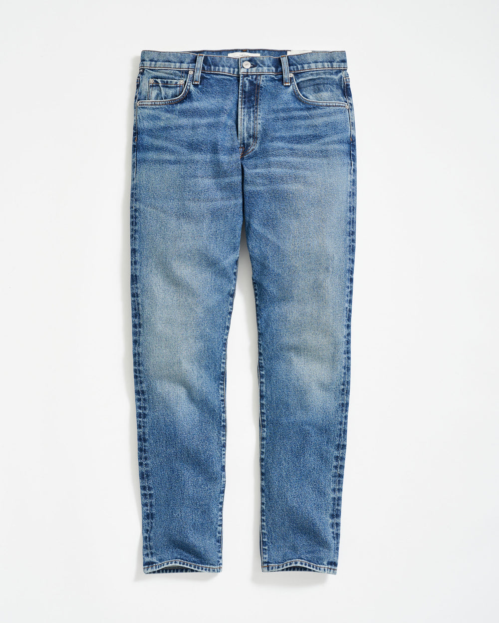 A pair of classic blue denim jeans with a slight faded effect, front pockets, belt loops, and a button fly, laid flat on a white background.