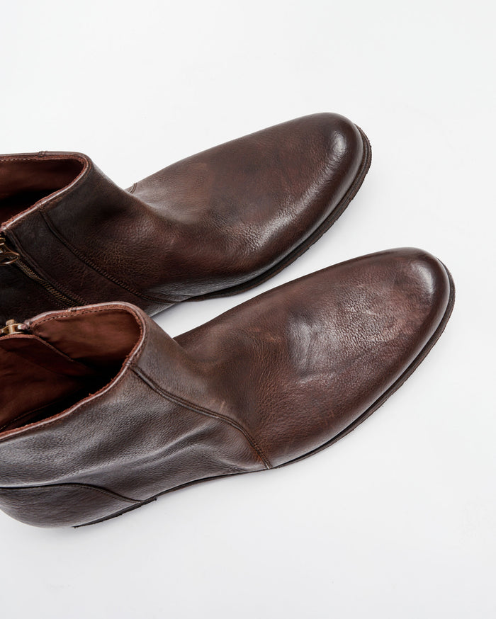 A pair of brown leather ankle boots with side zippers, shown from above on a white background.