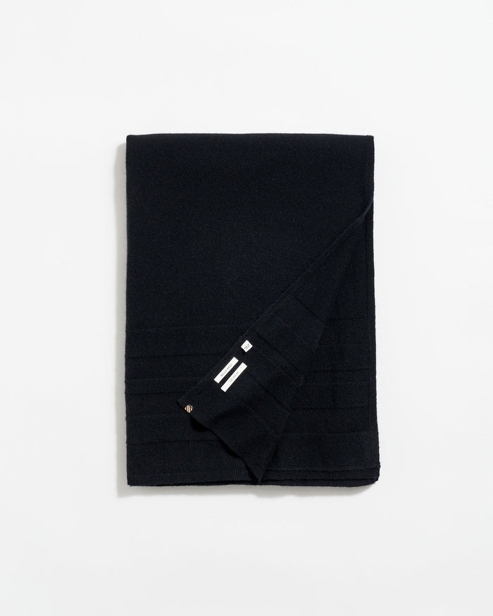 A neatly folded black scarf with subtle horizontal lines and a small section showing three white stripes near the corner, displayed on a plain white background.