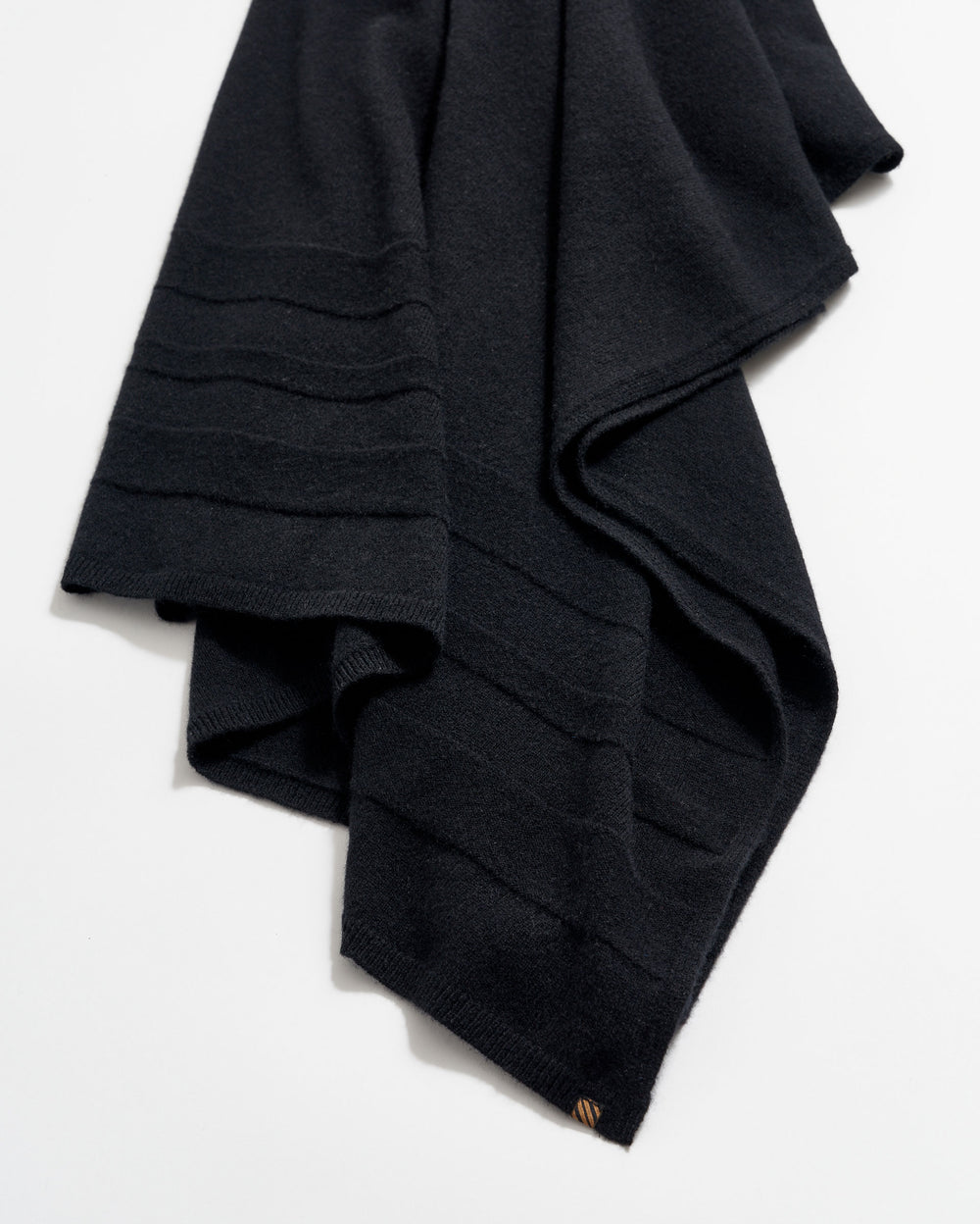 A folded black wool scarf with subtle horizontal ribbed lines, displayed on a white background.