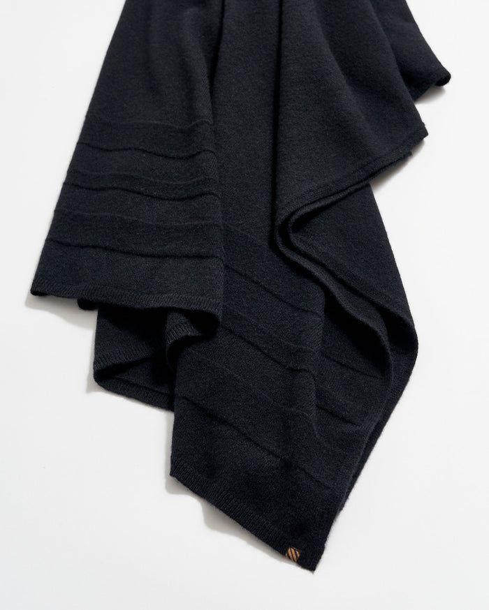 A folded black wool scarf with subtle horizontal ribbed lines, displayed on a white background.