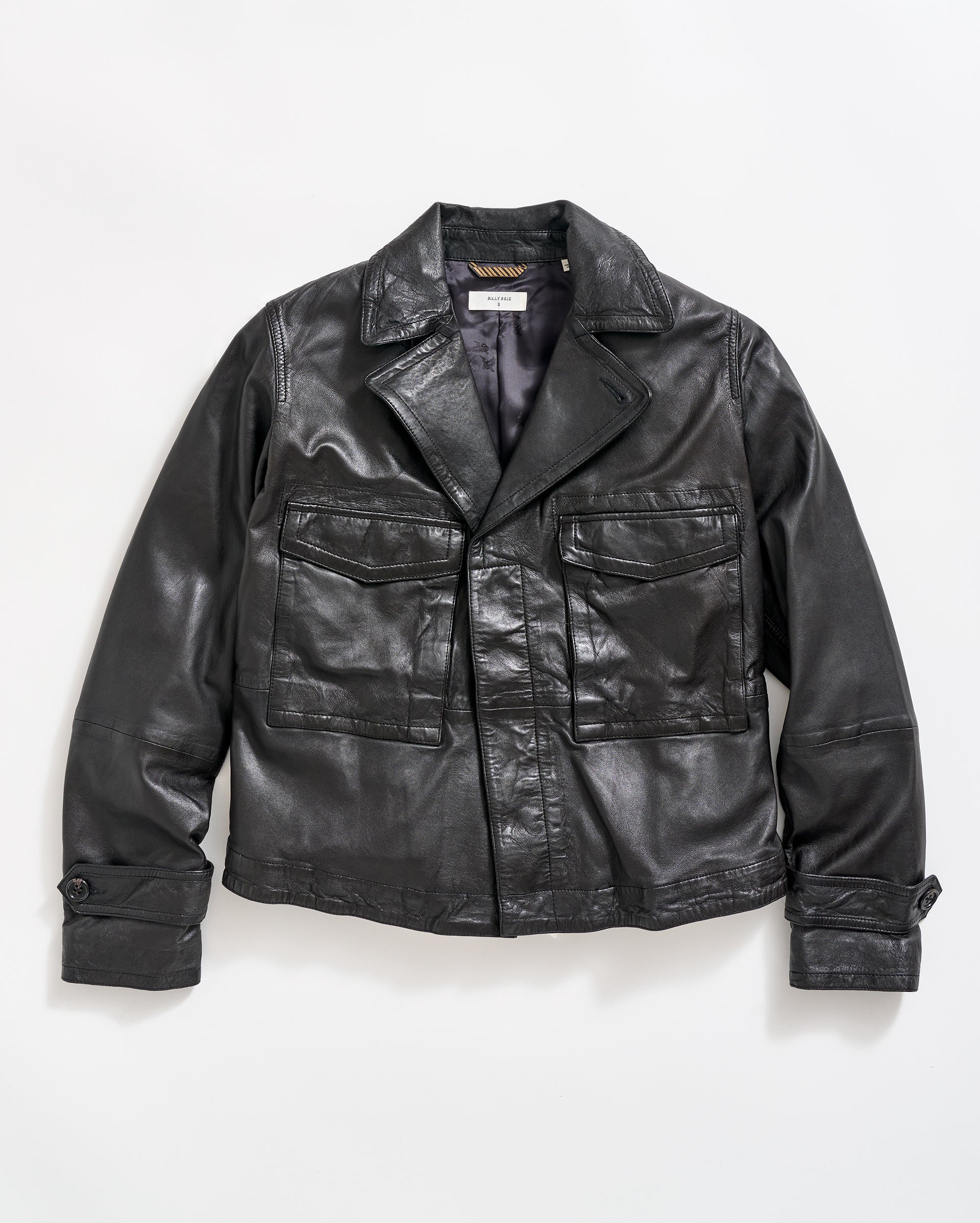 A black leather jacket with large front pockets, buttoned cuffs, and a notched collar, laid flat on a white background.