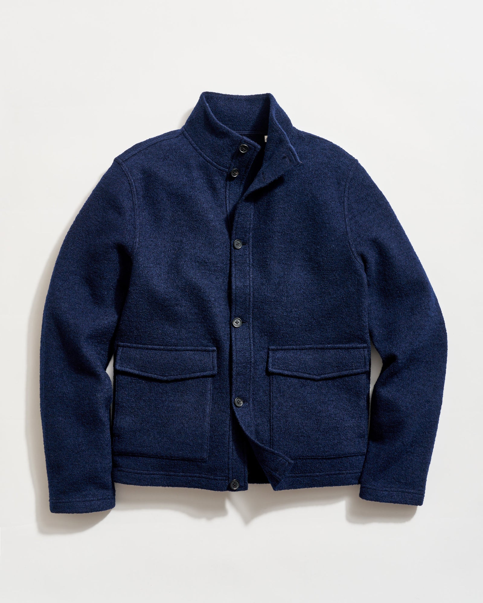 A navy blue wool jacket with a stand-up collar, button-front closure, and two large front flap pockets, laid flat on a white background.